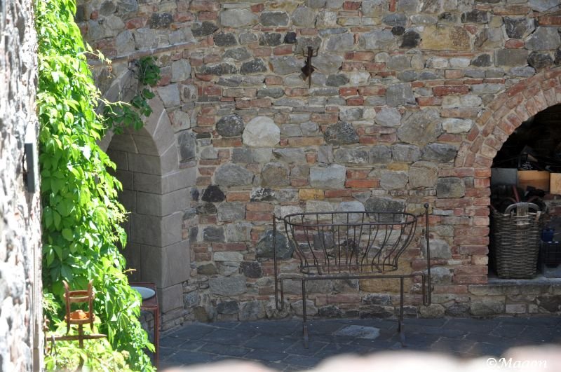 Castello Di Amorosa: каменная стена с арками и металлической корзиной